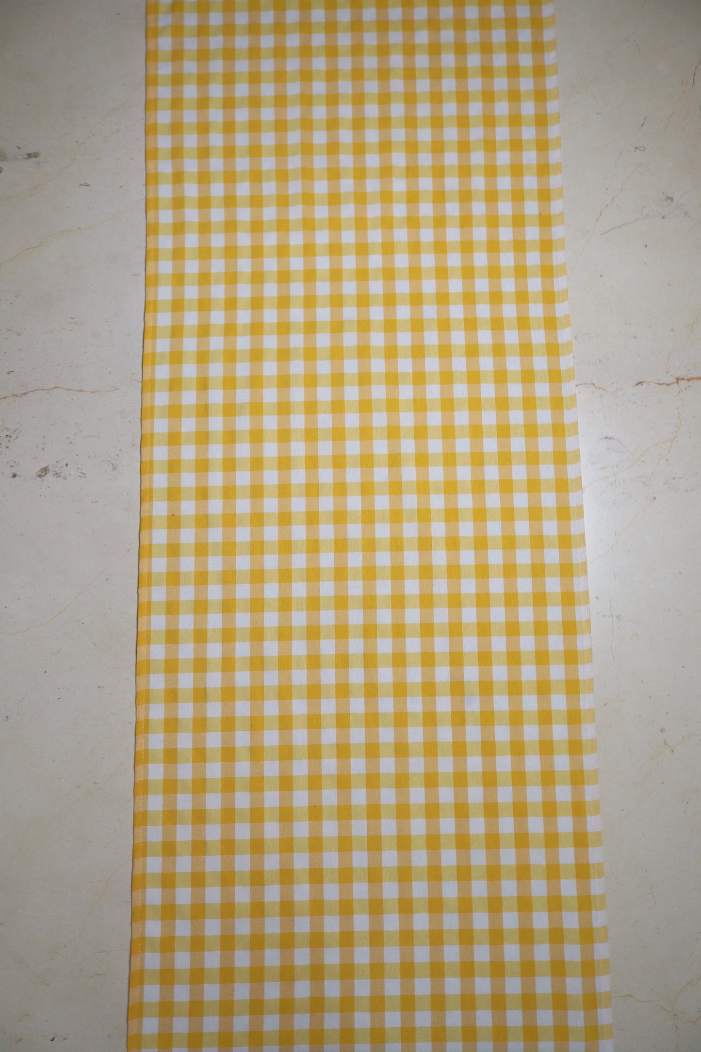 Camino de mesa con diseño de cuadros amarillo y blanco sobre mesa de comedor
