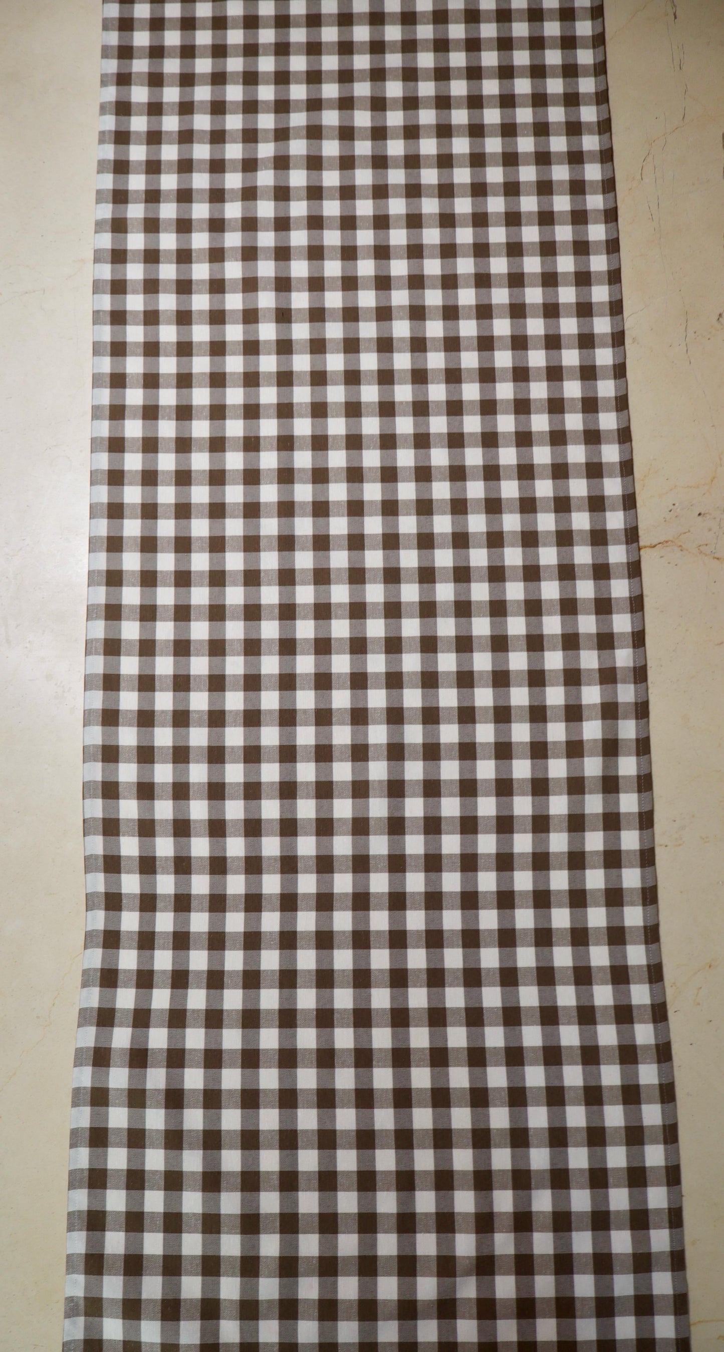 Camino de mesa con diseño de cuadros café y blanco sobre mesa de comedor