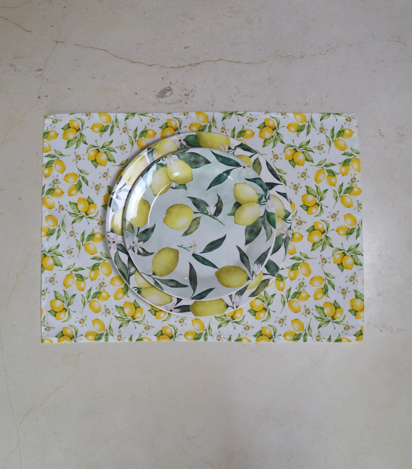 Mantel individual con estampado de limones sobre mesa con vajilla estampada