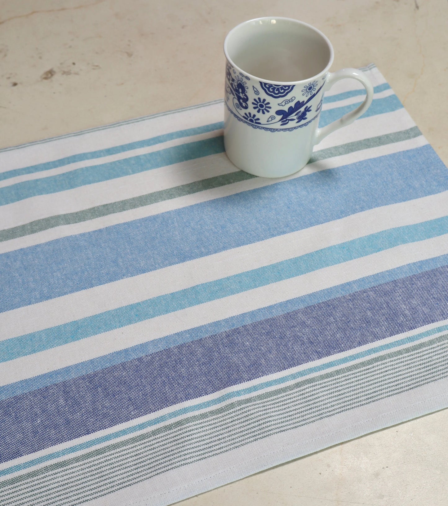 Mantel individual rayas azul y blanco sobre mesa de comedor