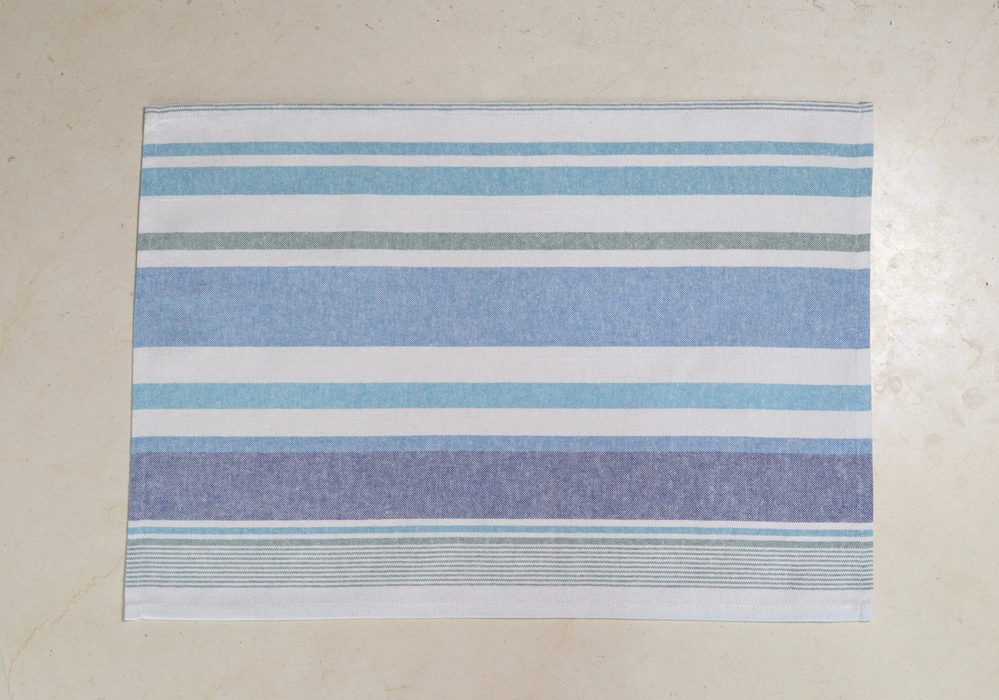Mantel individual con diseño de rayas azul y blanco sobre mesa de mármol