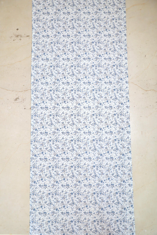 Camino de mesa con diseño floral en tonos azules sobre fondo blanco sobre mesa
