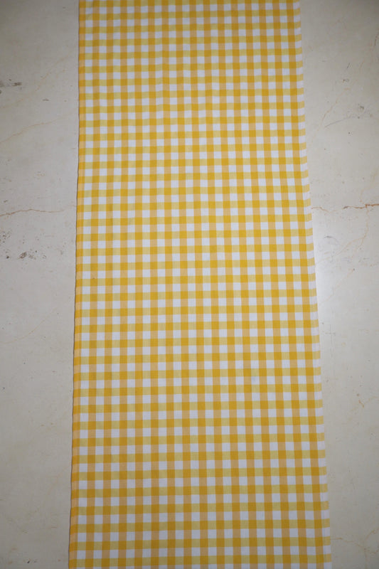 Camino de mesa con diseño de cuadros amarillo y blanco sobre mesa de comedor
