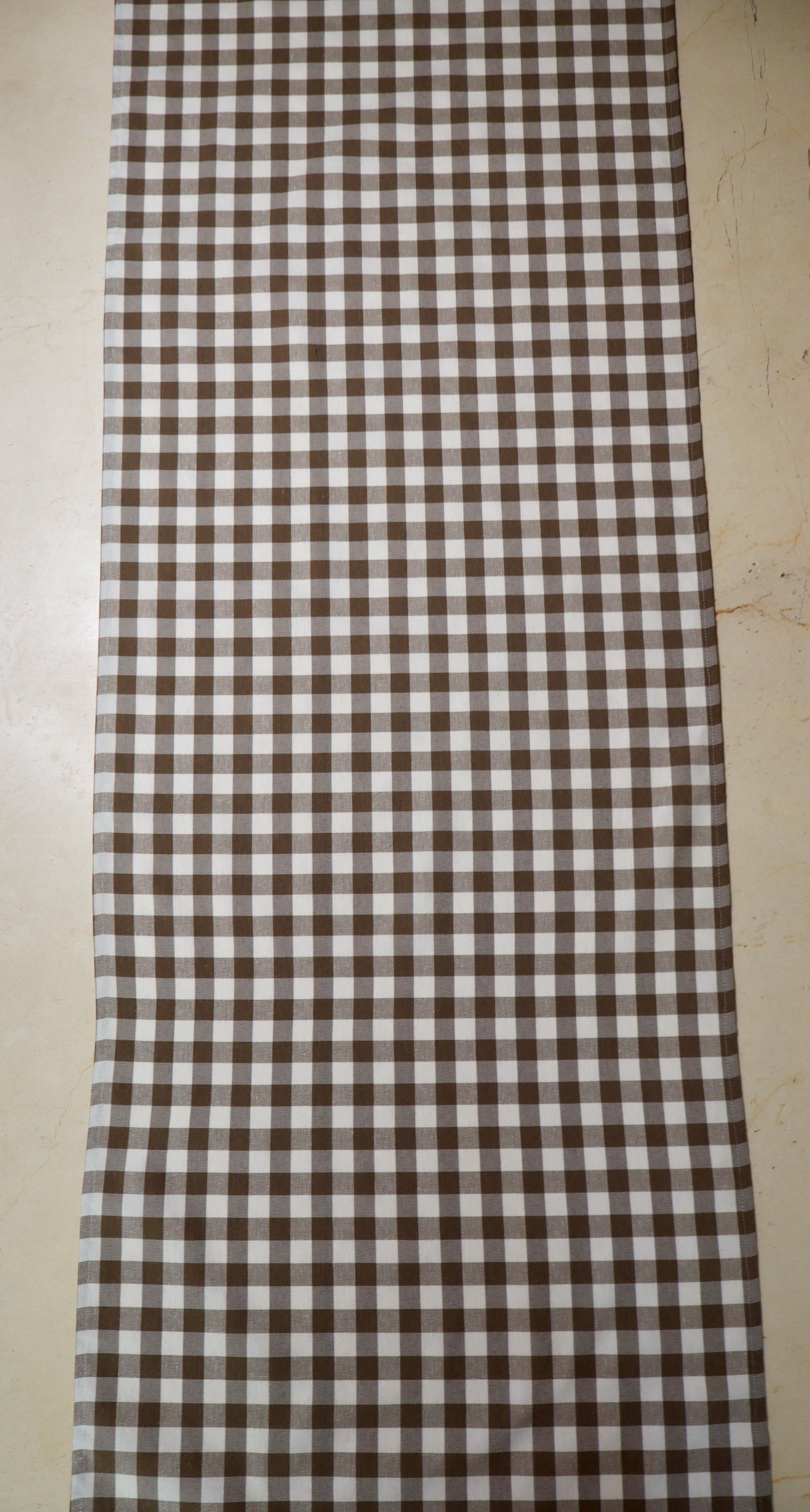 Camino de mesa con diseño de cuadros café y blanco sobre mesa de comedor
