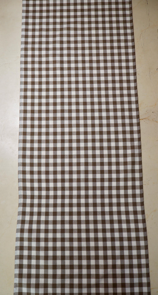 Camino de mesa con diseño de cuadros café y blanco sobre mesa de comedor
