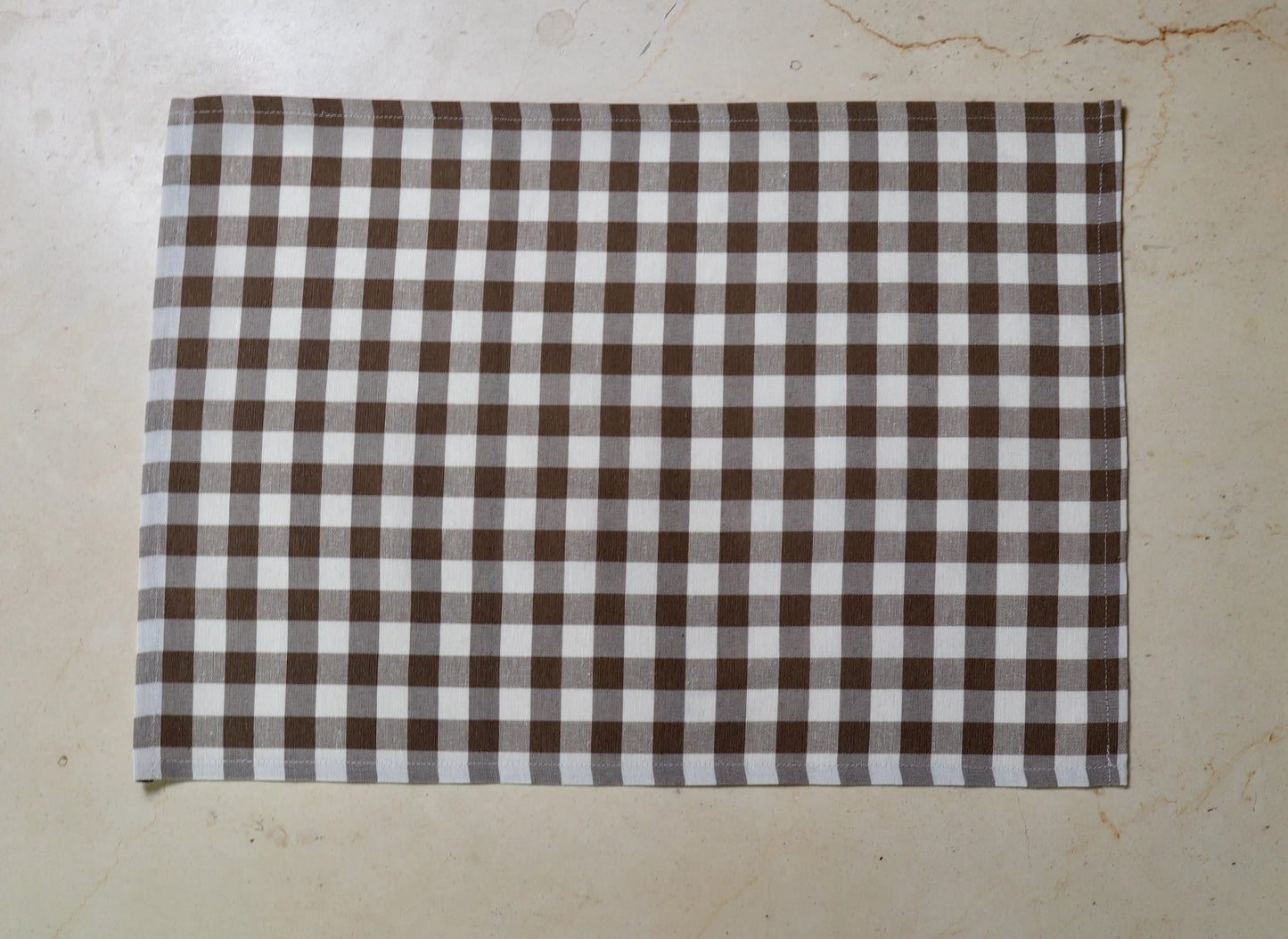  Mantel individual con diseño de cuadros café y blanco sobre mesa de comedor

