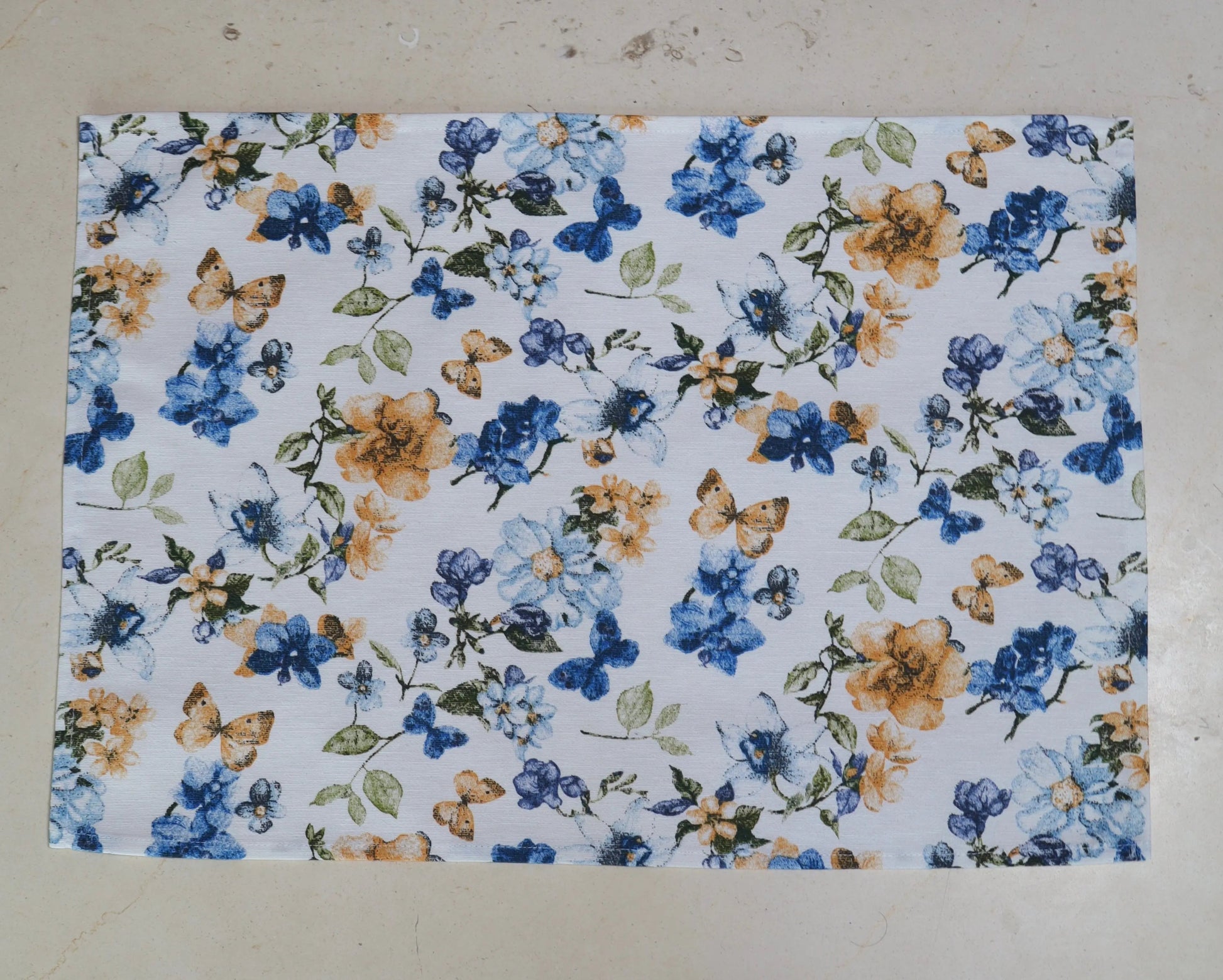 Mantel individual con estampado floral azul y blanco sobre mesa de comedor

