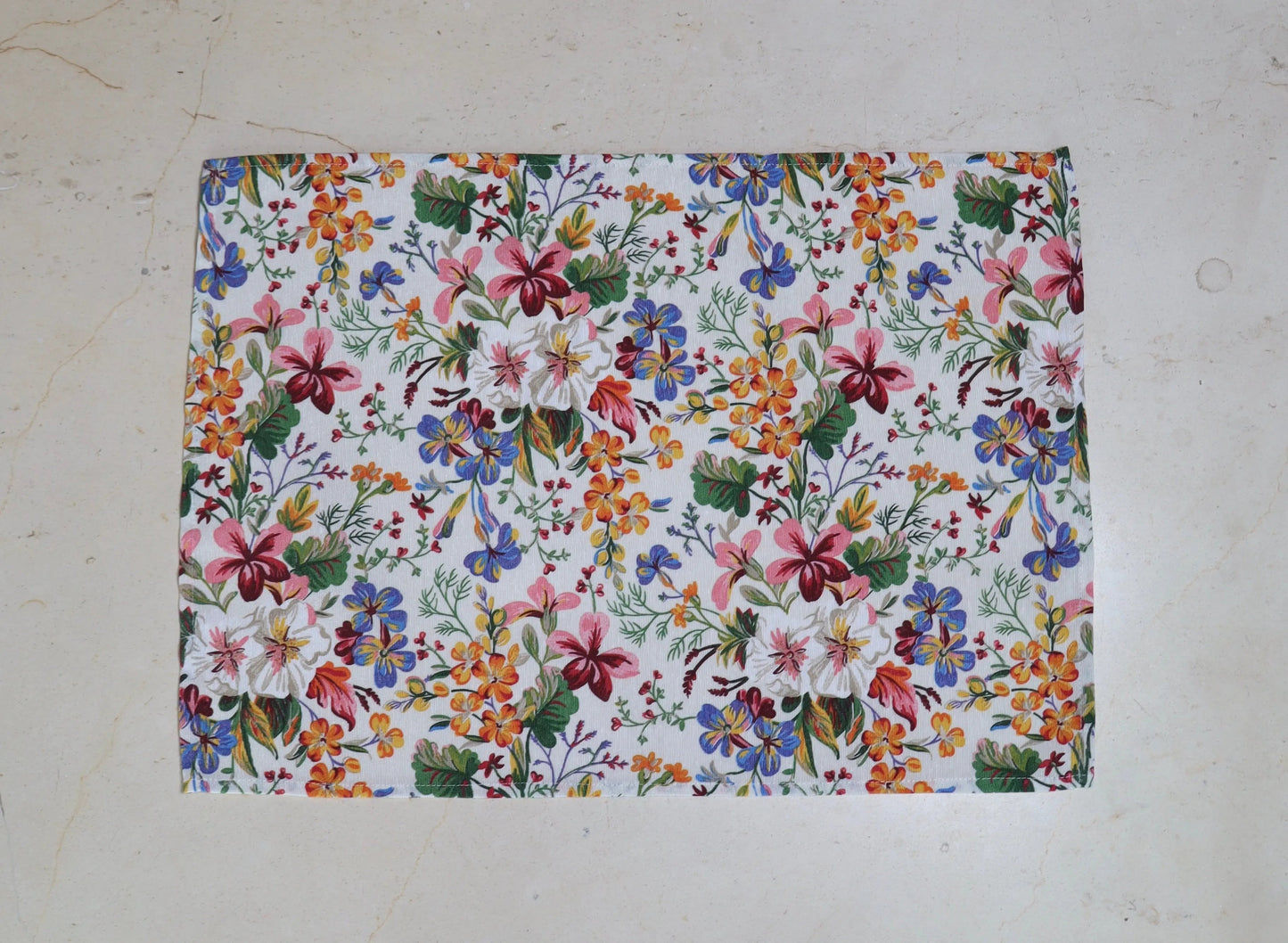 Mantel individual con estampado floral multicolor sobre mesa de comedor
