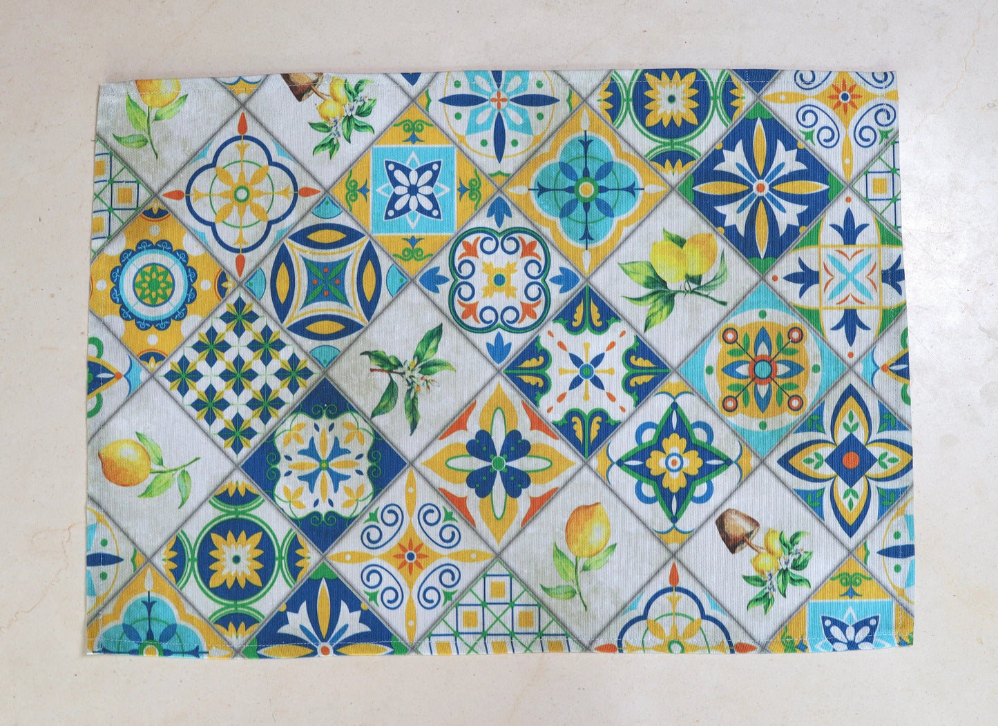 Mantel individual con diseño de azulejos en tonos amarillo, verde y azul sobre mesa de comedor

