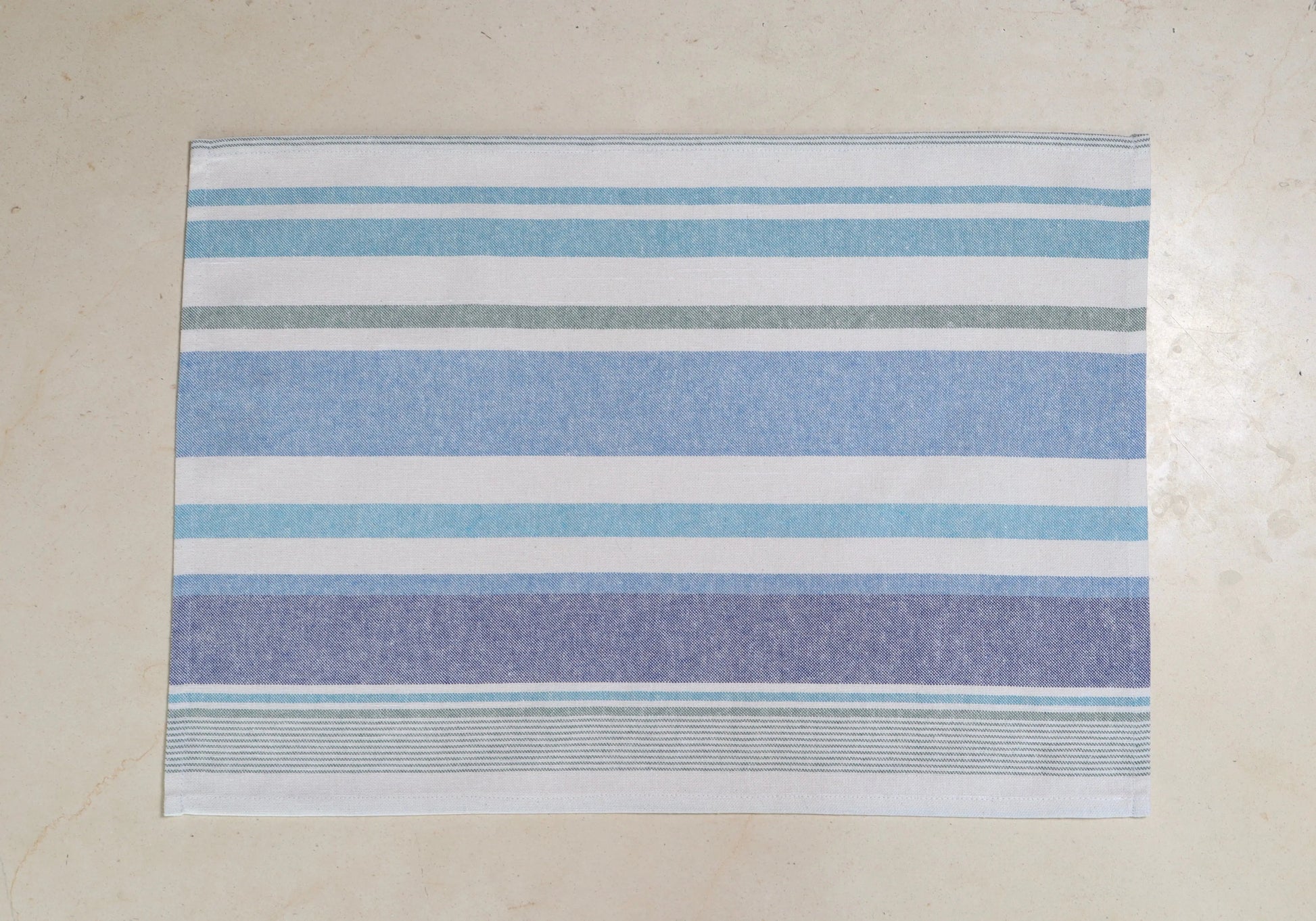 Mantel individual con diseño de rayas azul y blanco sobre mesa de mármol
